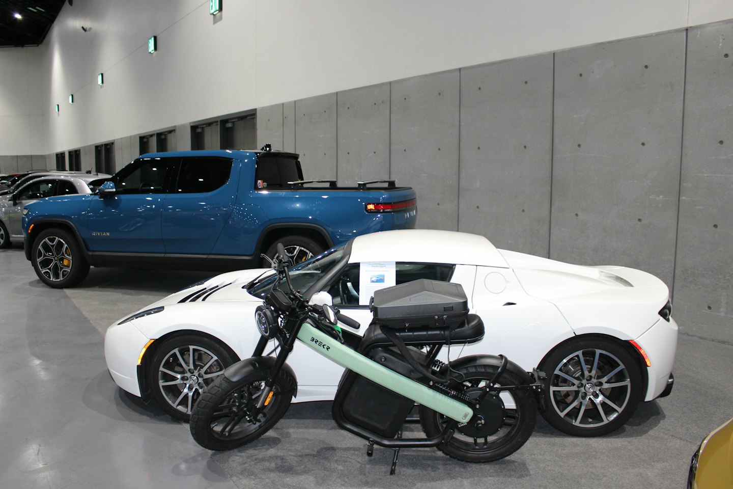 Grüner Elektroroller vor Autos in einem Showroom geparkt.