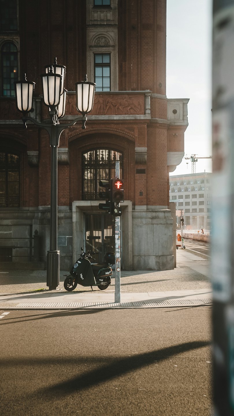 Ein Elektroroller parkt auf einem Bürgersteig vor einem Backsteingebäude.