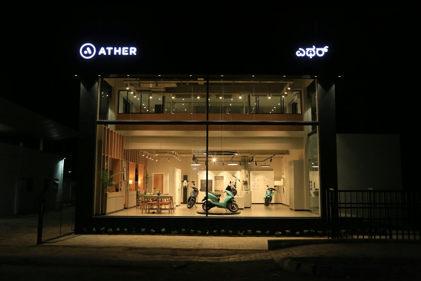 Moderner Showroom für Elektroroller bei Nacht mit ausgestellten teal Rollern.