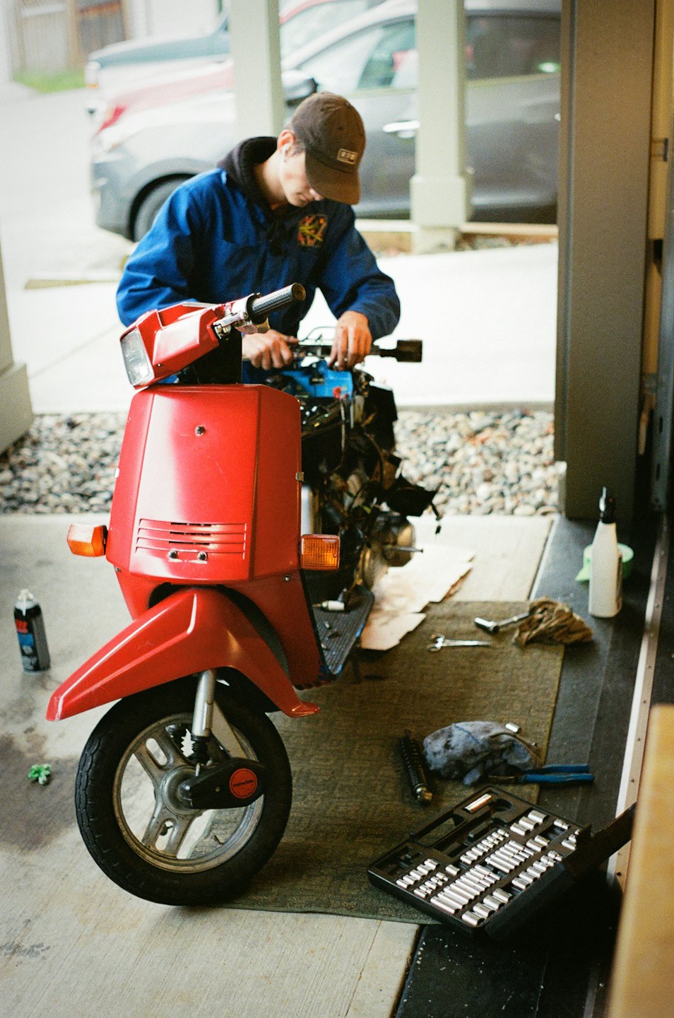 Mechaniker repariert den Motor eines roten Rollers in einer Werkstatt mit Werkzeugen.